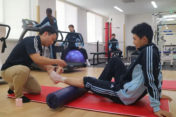 理学療法士を目指す和泉大学の学生がスポーツリハビリの実習を行っている様子。足にテーピングを巻いている。