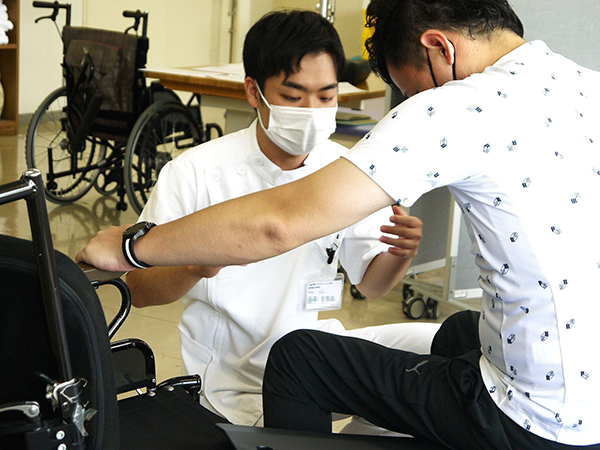 車いすから立ち上がるサポートをしている理学療法士の様子
