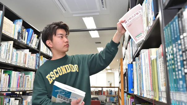理学療法士を目指す学生が図書館で参考書を選んでいる様子